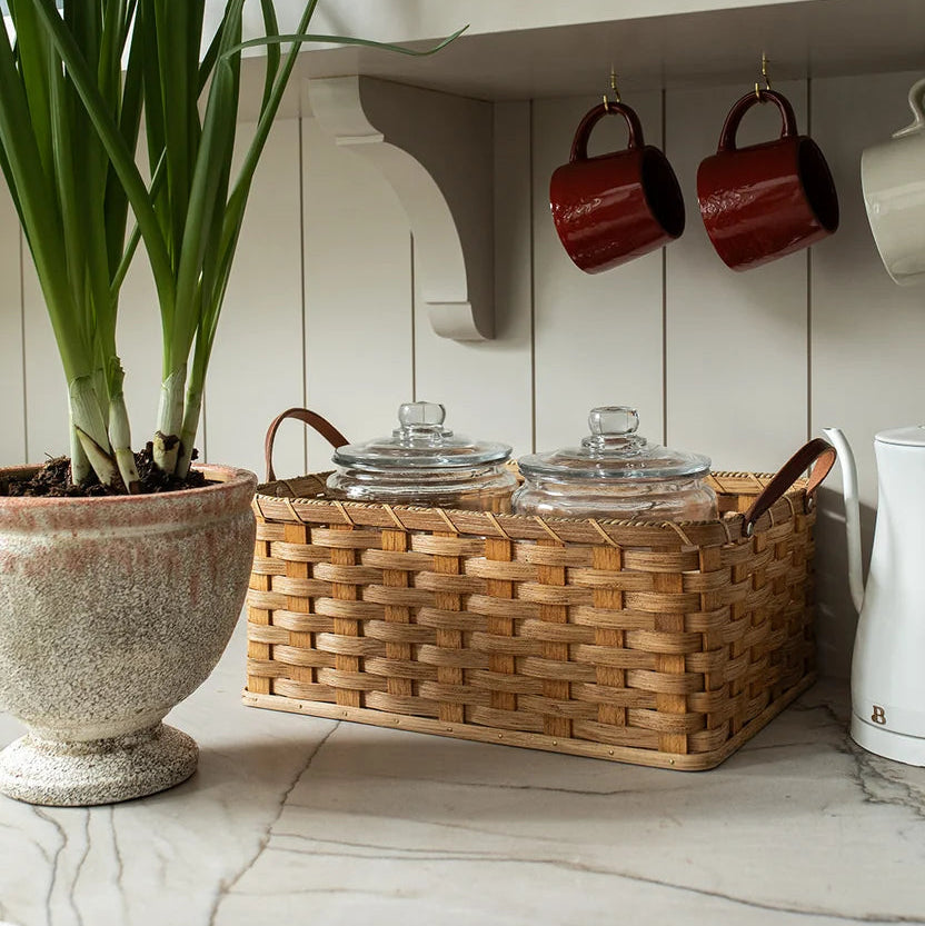 Kitchen counter with a woven basket, glass jars, and a potted plant.