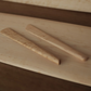 Two wooden cheese knives with bird's-eye maple pattern lying on a light wooden surface.