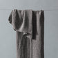 Gray textured towel hanging on a line against a gray background
