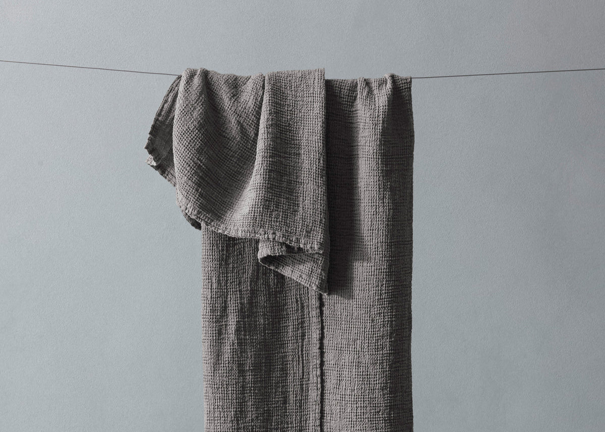 Gray textured towel hanging on a line against a gray background
