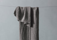 Gray textured towel hanging on a line against a gray background